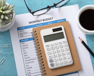 Calculator laying on top of a paper with a budget