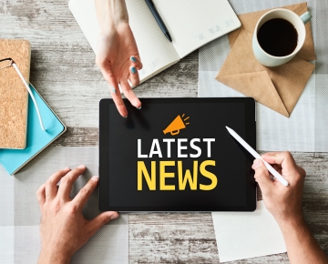 tablet saying latest news with hands hovering over it