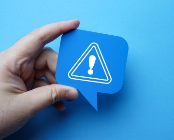 hand holding sign with exclamation point with blue background