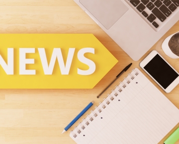 news written on desk next to laptop, notepad, phone, coffee