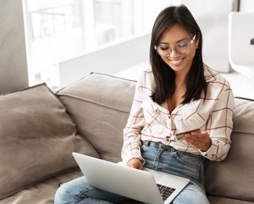 Woman on Couch Holding Credit Card