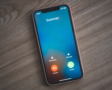 cell phone ringing on wood table with call from scammer