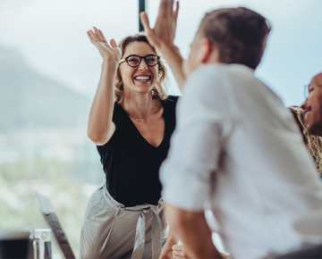 woman in black shirt and glasses high fiving coworkers