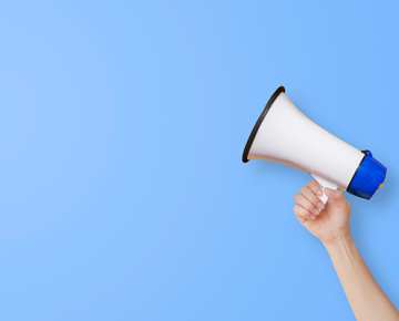 hand holding megaphone against light blue background