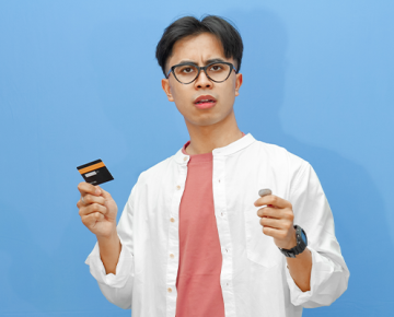 man holding credit card and coin against blue background
