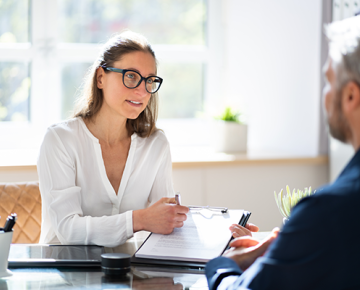 woman in white top with papers explaining something to man