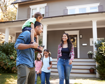 family outside of home with child on dad's shoulders