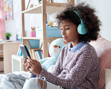 young girl wearing headphones and looking at phone